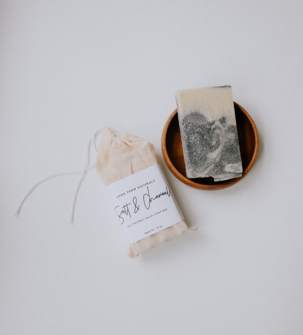 bar soap in wooden bowl with packaged soap laying next to it