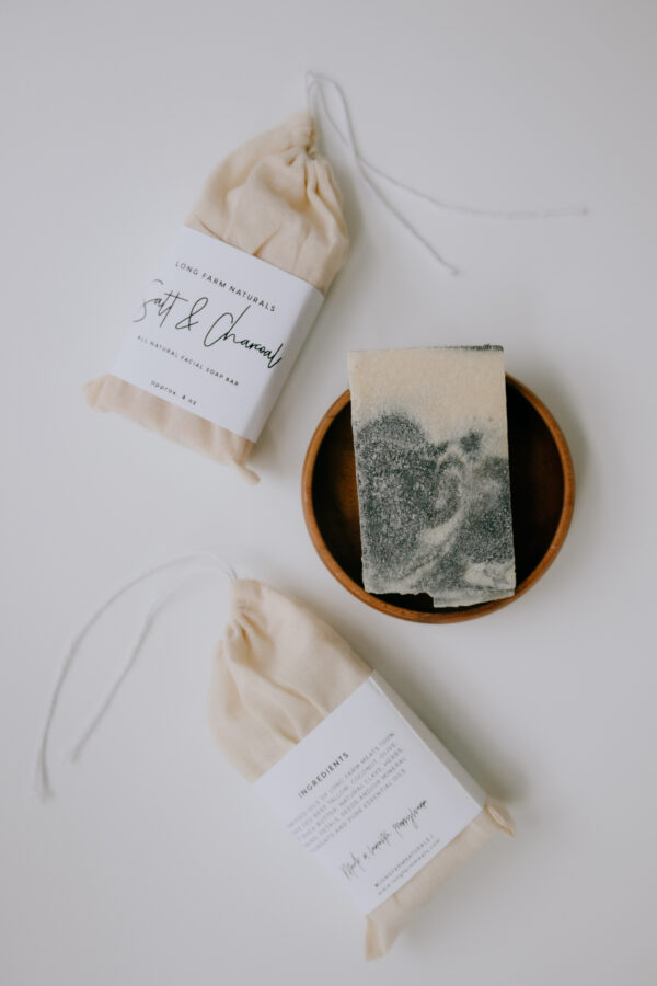 textured facial soap in a wooden bowl with soap packaging around it